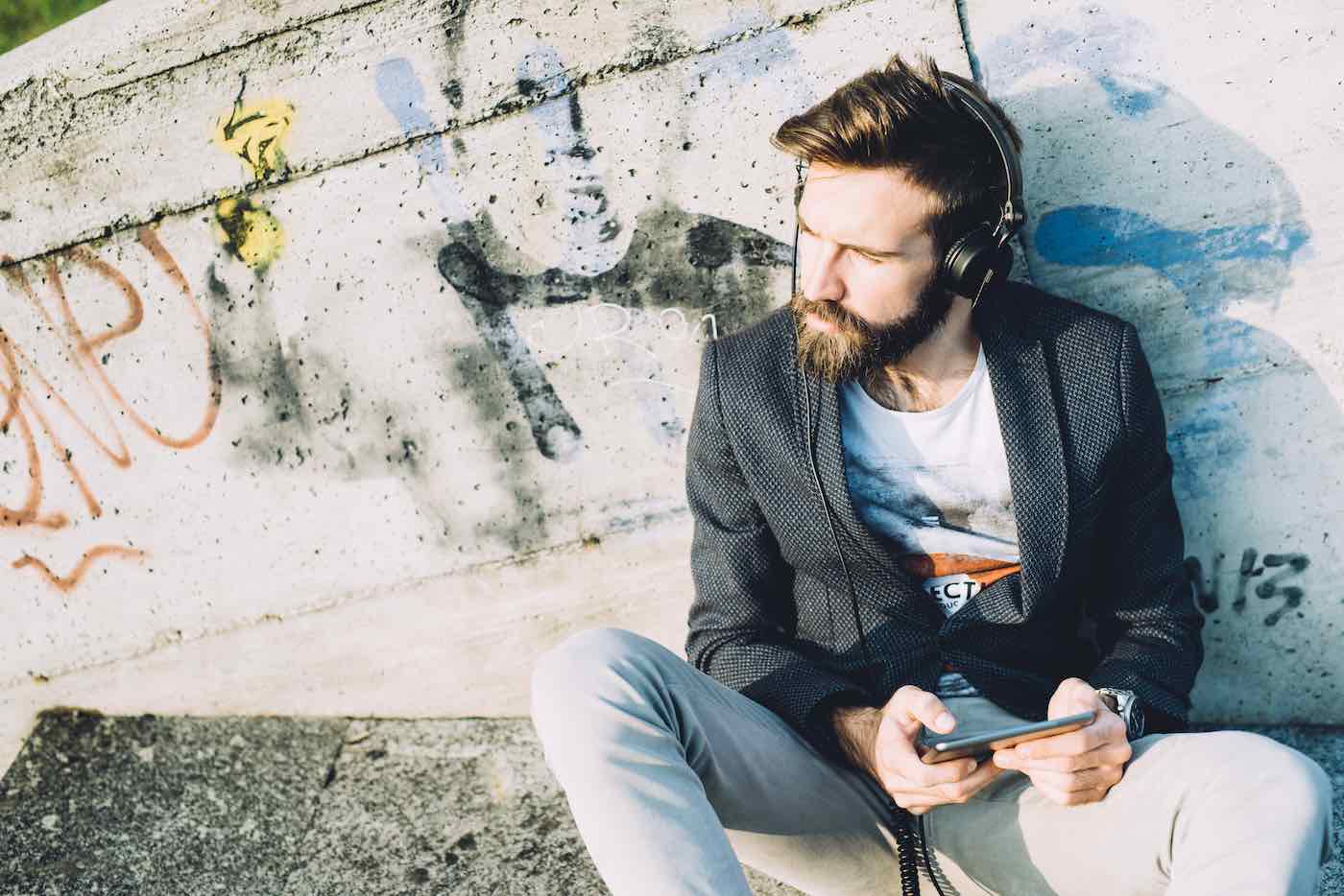 Young bearded man using tablet listening music